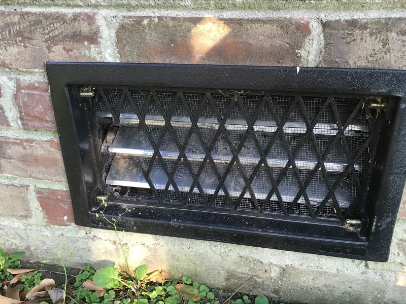 A metal grill over a vent in bricks